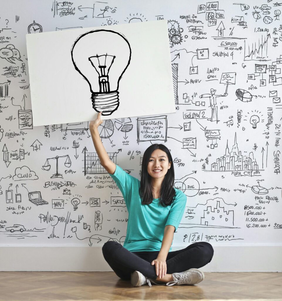 Une enseignante assise devant un mur illustré d’idées et d’une ampoule, représentant la créativité pédagogique.