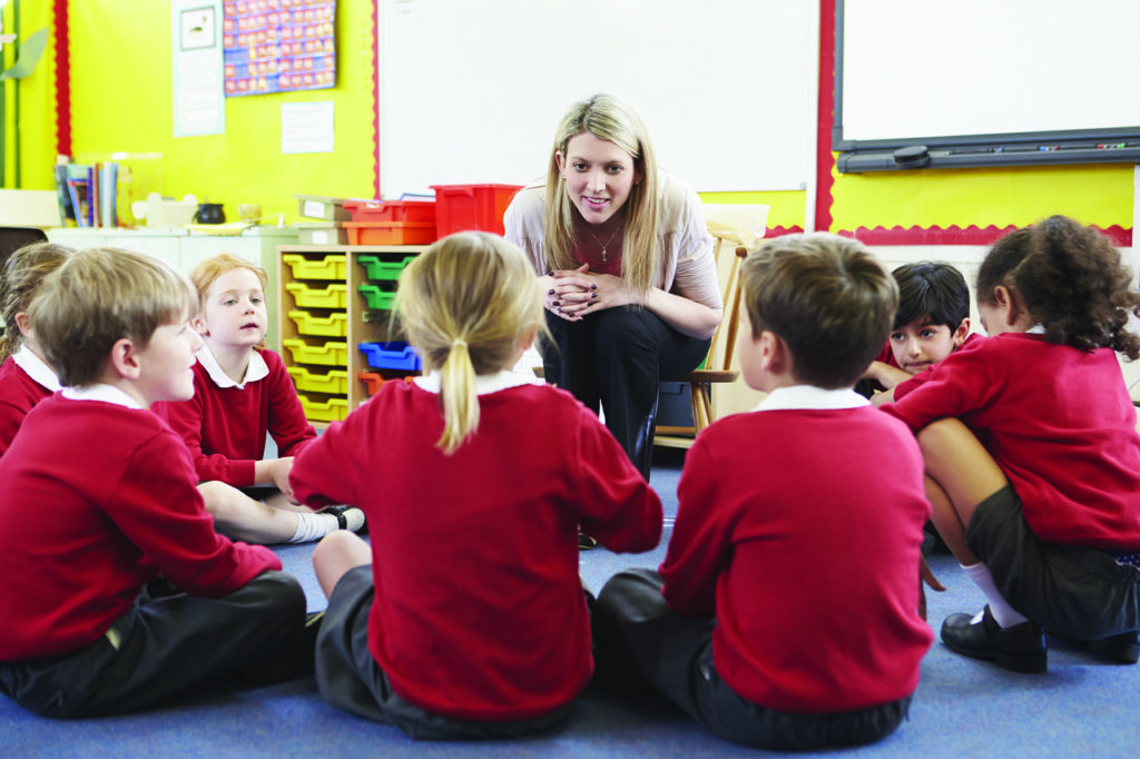 Enseignante avec un groupe d'élèves en classe de primaire, apprentissage collectif